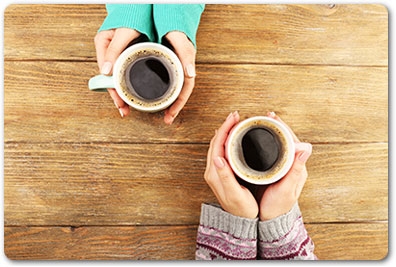 Image of two women's hands holding coffee cups